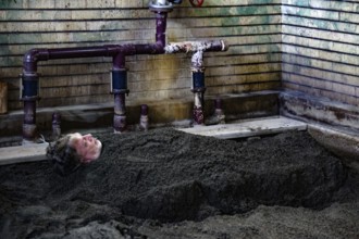 Person buried in sand in traditionally designed onsen area, Beppu, Takegawara Onsen, Japan