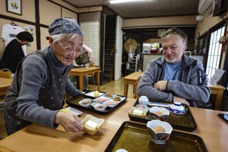Ryokan landlady serving traditional Japanese breakfast on trays, Kazurabashi, Iya, Japan