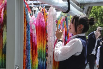 Schoolgirl arranges colorful paper cranes at the Peace Monument in Peace Park, Hiroshima, Japan