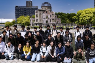 Group of students posing in front of the Hiroshima Memorial in bright sunshine, Hiroshima, Japan