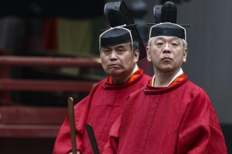 Two priests in traditional red robes and wearing Kanmuri hats in the courtyard of Toshogu Shrine,