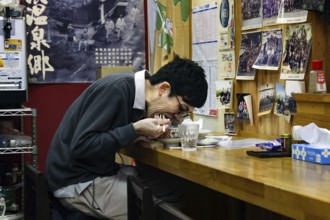 Man eating ramen in Japanese restaurant with traditional decorations, Yamanouchi, Japan