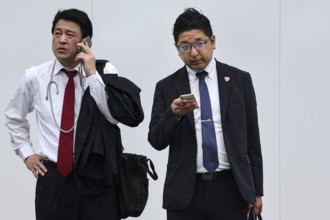 Two businessmen in suits, one talking on the phone, the other using a smartphone, Tokyo, Minato,