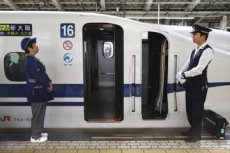 Shinkansen in front of departure from Central Station, accompanied by two railway employees in