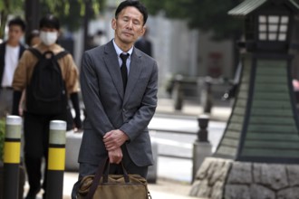 Businessman in a suit holding a bag and standing on a street, Tokyo, Minato, Japan
