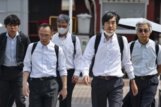 Group of business people in suits walking down the street together, Tokyo, Minato, Japan