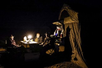 Camp at night with lights, people, vehicle in desert environment, Oodnadatta Track, Australia