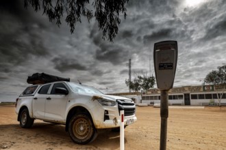 Off-road vehicle next to a parking meter under dramatic sky in William Creek, William Creek, South