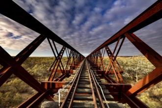 Perspective view of a steel girder bridge with railroad tracks under cloudy sky, Oodnadatta Track,