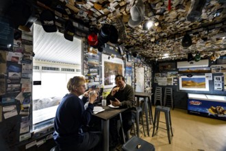 Two people in the warmly decorated and cozy interior of the William Creek Hotel, William Creek,
