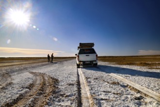 Off-road vehicle drives across a wide salt lake under clear skies, South Australia, Australia