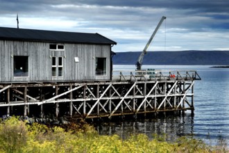 Wooden building on the water in Hamningberg under cloudy sky