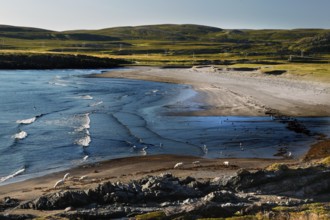 Waves roll onto a secluded beach surrounded by green hills, N Hamningberg, zero