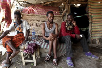 Three men sit relaxed in a café in Ahmedela surrounded by traditional decor, Ahmedela, Ethiopia