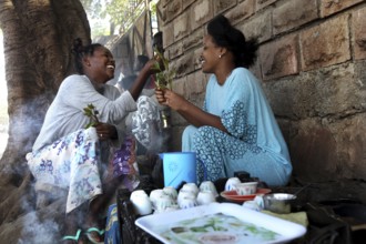 Two woman enjoy a traditional coffee ceremony and share moments of laughter, Asbe Teleri, Afar,