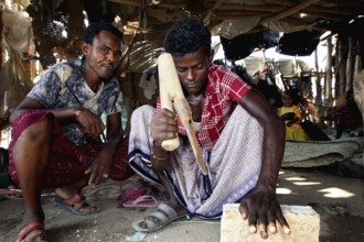 Muhammad's brothers work on a salt block in the hut, Ahmedela, Tigray, Ethiopia