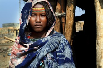 Aishe stands in front of Muhammad's Hut, Ahmedela, Tigray, Ethiopia