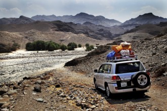 A land cruiser drives through the barren desert landscape of Ahmedela