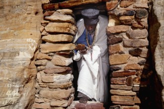 Priest in traditional dress enters the rock church Abba Daniel Krokor, null