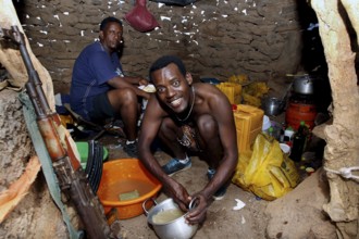 In the hut at Erta Ale Camp, two men are immersed in their work surrounded by kitchen appliances,