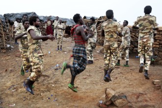 Soldiers dance in their military uniforms on rocky ground at Erta Ale Camp, Erta Ale, Ethiopia