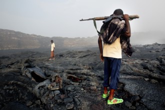 Members of the escort crew cross the volcanic terrain of Erta Ale, Erta Ale, Afar, Ethiopia