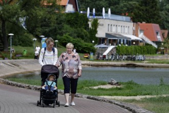 Two woman with strollers along the lagoon promenade in Nida on a summer day, Nida, null, Lithuania