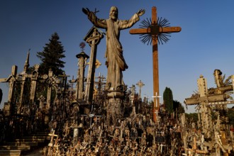 Hill of Crosses in Siauliai with countless crosses and religious symbols in the evening light,