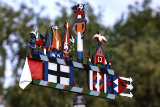 Colourful Kuren pennant with folk symbols in front of blurred trees, Juodkrante, Klaipeda,