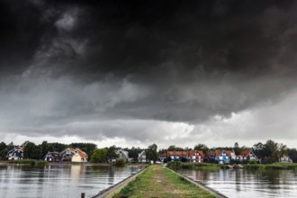 Pier leads to a village under a dramatic sky in Pervalka, Pervalka, Lithuania