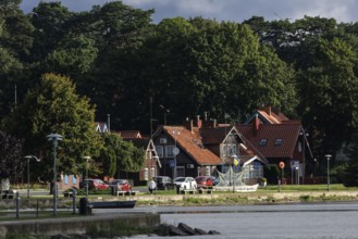 Picturesque red brick houses on the water surrounded by thick green forests, Juodkrante, Klaipeda,