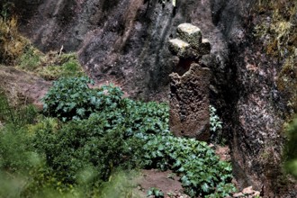 Cross in rocky surroundings surrounded by shrubs, symbolic representation in Lalibela, Lalibela,