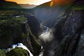 The Vøringsfossen Waterfall in Måbødal appears dramatically in the light of a magnificent sunset,
