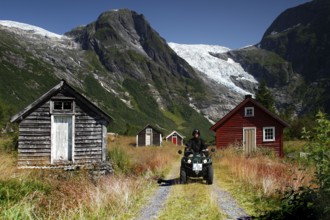 Scene near the Bøyabreen glacier with rustic huts and ATV against an impressive mountain backdrop
