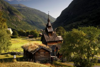 The historic Borgund Stave Church nestled in green countryside and surrounded by mountains,