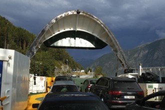 Ferry in Eisdal with cars on board surrounded by dramatic clouds and mountains, Valldal, Møre og