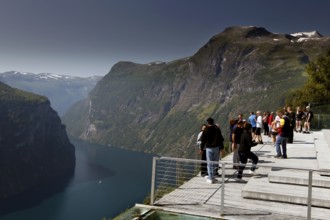 Tourists stand on an observation deck and enjoy fjord views, Geirangerfjord, Norway