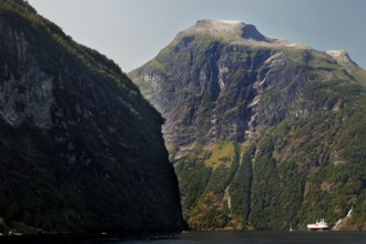 View of steep mountain walls and a Hurtigruten ship in the fjord, Geirangerfjord, Norway