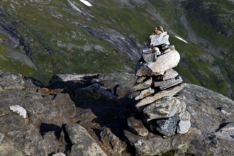 Stone pyramid on rocky outcrop with green hills in the background, Geirangerfjord, Dalsnibba,