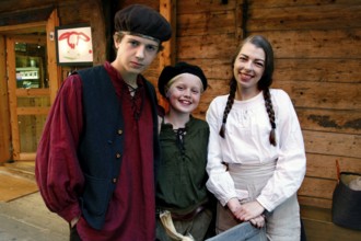 Group of people wearing traditional clothes in a historic wooden house alley, Bergen, Norway
