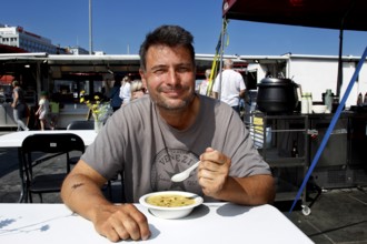 Smiling man eating at fish market in sunshine, Bergen, Hordaland, Norway