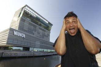 A man poses in front of the Munch Museum in a well-known screaming pose, Oslo, Bjøvika, Norway