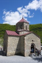 Stone church in rural area with visitors at the entrance under clear skies, Kvemo Mleta Lomis dome