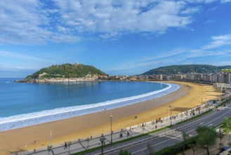 La concha beach curving along the bay of san sebastian city, with people walking on the sand and