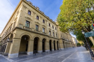 Gipuzkoa square facade in san sebastian with repeating stone arches and windows along a tree lined