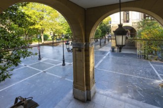 Arched arcade entrance providing a view through to gipuzkoa square park in san sebastian, featuring