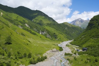Wide mountainous landscape with river surrounded by lush greenery under a cloudy sky, White Aragvi