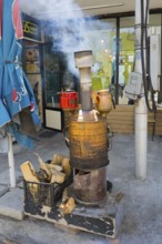 A smoking iron samovar stands in front of a café surrounded by wood, making tea near Gudauri,