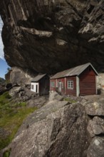 Historical wooden houses sheltered under a massive rock overhang. Summer, Helleren (Helleren),