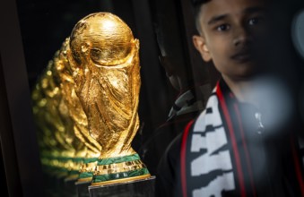 A football fan poses for a photograph with the original FIFA World Cup 2026 Trophy during the